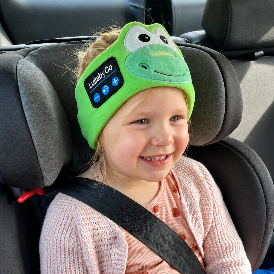 A smiling child wearing the CozyLullaby frog headband in a car seat